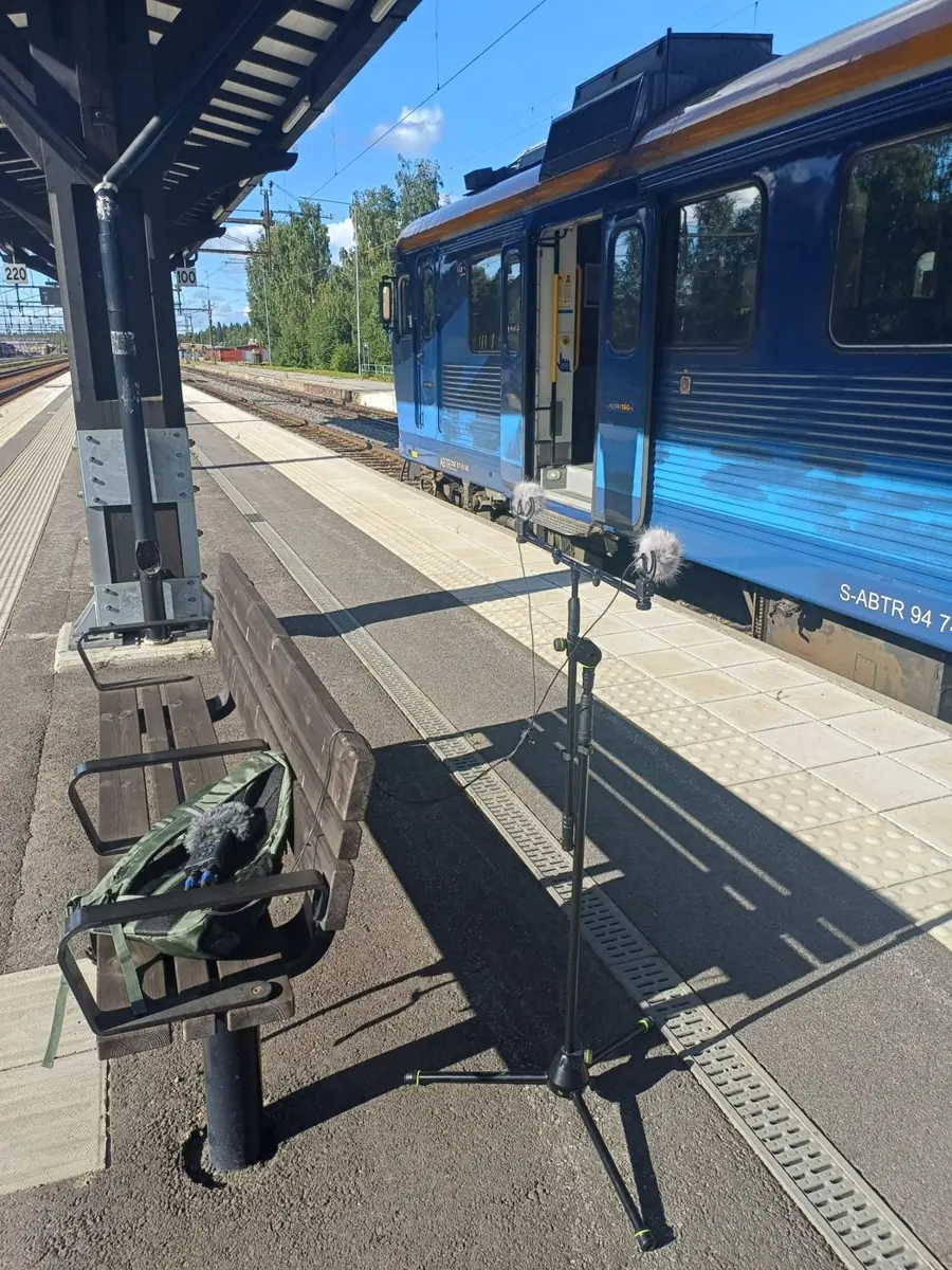 A microphone stand on a railway platform beside a blue regional train